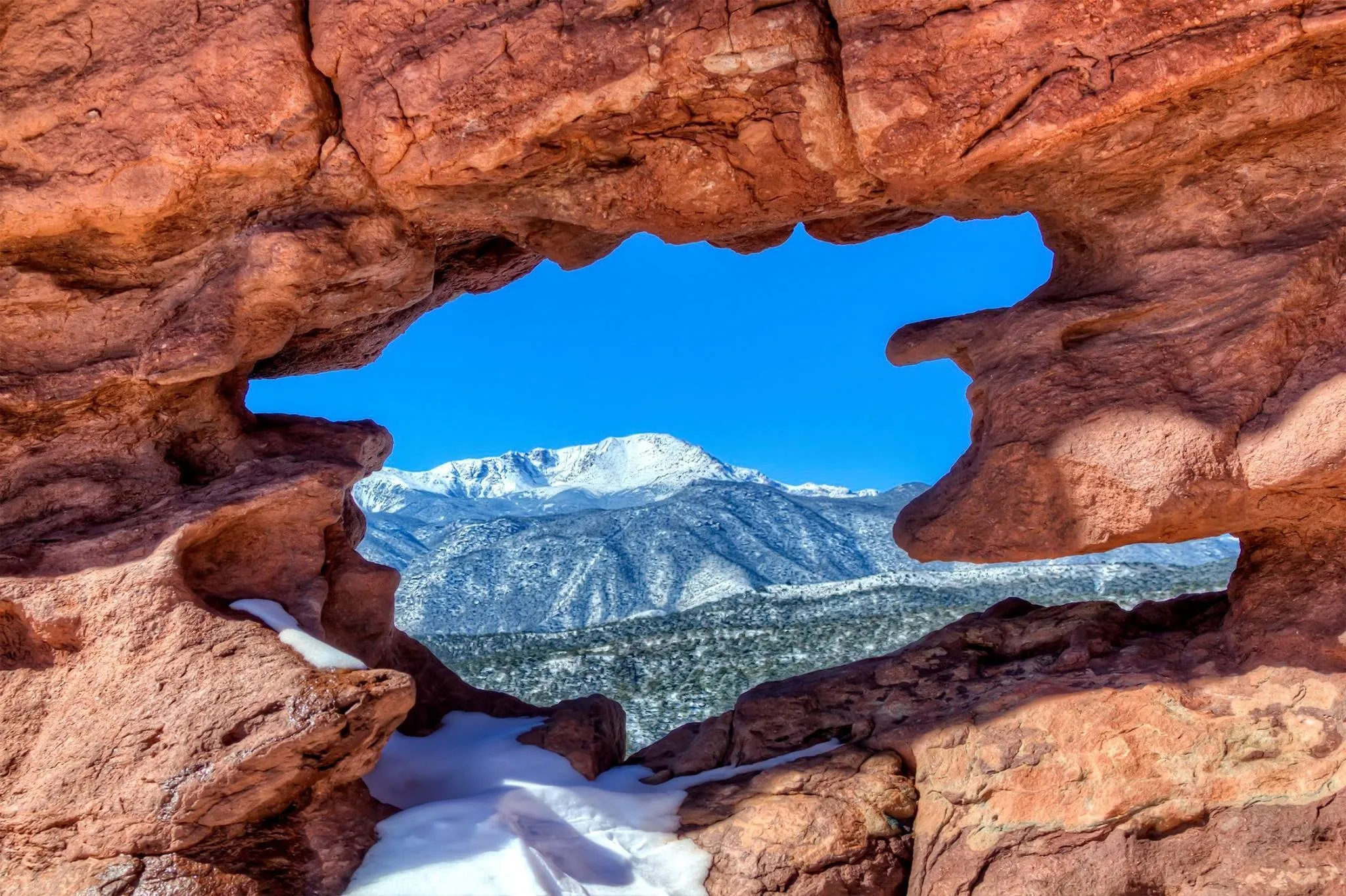 Pikes Peak seen through a hole in a sandstone formation at Garden of the Gods, Colorado Springs, USA.